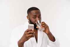 渴了年轻的非洲男人。持有玻璃喝水身体健康孤立的白色工作室背景