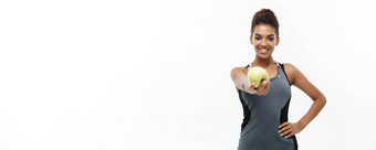 健康的健身概念美丽的美国非洲夫人<strong>灰色</strong>健身衣服持有绿色<strong>苹果</strong>孤立的白色背景
