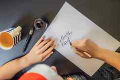 快乐圣诞节快乐一年书法家年轻的女人写短语白色纸买或卖股票观赏装饰信书法图形设计刻字笔迹创建概念