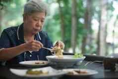 上了年纪的高级女人吃食物阳台成熟的退休生活方式