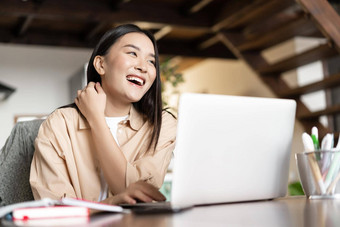 快乐亚洲女人笑工作移动PC首页女孩学生研究电脑在线学习远程教育概念