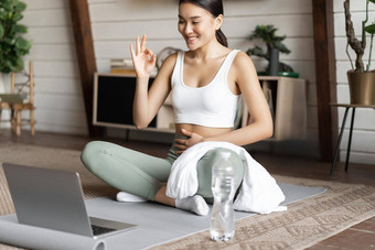 冥想在线类概念年轻的女人培训远程首页坐着橡胶席生活房间移动PC瑜伽