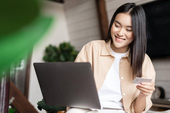 互联网购物年轻的亚洲女人<strong>支付</strong>在线购买信贷卡移动PC坐着首页