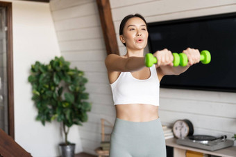 健身亚洲女孩锻炼<strong>首页</strong>生活房间提升哑铃穿<strong>运动服</strong>体育运动活动