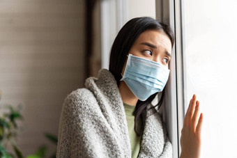 生病的亚洲女孩医疗脸面具站窗口向往检疫生病了科维德流感