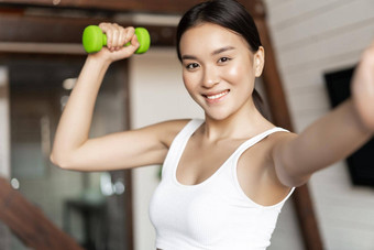 微笑朝鲜文女孩采取自拍哑铃锻炼<strong>首页</strong>流感大流行穿<strong>运动服</strong>