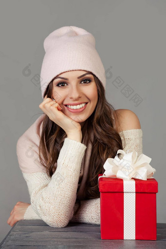 微笑快乐美丽的年轻的女人冬天衣服红色的圣诞节礼物盒子灰色的背景女孩享受圣诞节购物满足一年购物出售概念