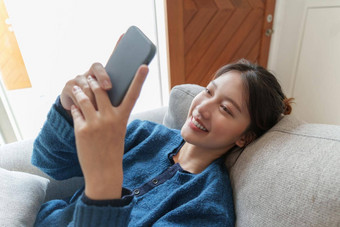肖像年轻的亚洲女人聊天朋友检查社会媒<strong>体智能</strong>手机坐着沙发上生活方式概念