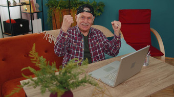 祖父男人。玩电脑视频游戏移动PC电脑赢了庆祝微笑幸福的