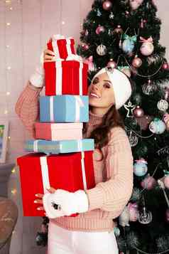 微笑快乐年轻的女人冬天衣服持有包装礼物盒子前面圣诞节树女孩享受圣诞节礼物问候一年圣诞节假期概念