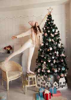 快乐年轻的女人装修圣诞节树女孩斯威亚