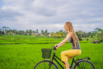 年轻的女人游乐设施自行车大米场乌布<strong>巴厘岛巴厘岛</strong>旅行概念