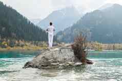 男人。站石头中心山湖实践瑜伽构成弗里克沙萨纳