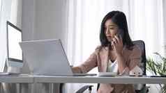 千禧年轻的女人坐着舒适的工作场所会说话的移动电话