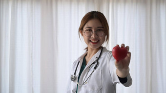 微笑女医生白色医疗统一的持有红色的心形状手医疗保健医疗概念