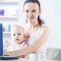 年轻的妈妈。婴儿移动PC沟通奶奶Skype