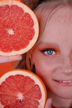 甜蜜的快乐的浅黑肤色的女人女人女孩女裁剪片葡萄柚皮肤脸橙色背景美味的多汁的水果热带柑橘类水果健康的食物重量损失
