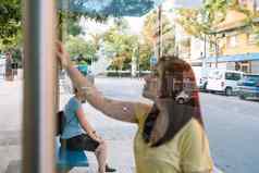 年轻的女孩等待城市公共汽车公共汽车停止女人检查公共汽车路线信息董事会照片玻璃