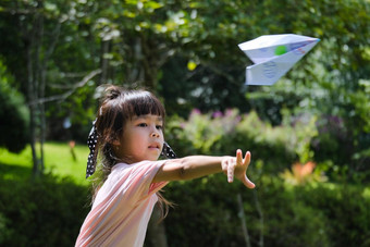 快乐孩子们玩纸飞机夏天花园可爱的女孩扔纸飞机公园快乐童年概念