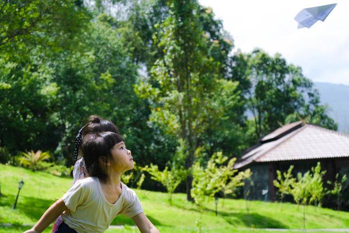 快乐孩子们玩纸飞机夏天花园可爱的女孩扔纸飞机公园快乐童年概念