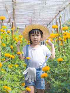 女孩穿他帮助妈妈。金盏花花园园丁可爱的女孩玩美丽的花花园