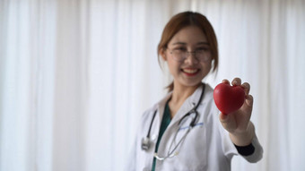 微笑女医生白色医疗统一的持有红色的心形状手心脏病学医疗保健医疗概念
