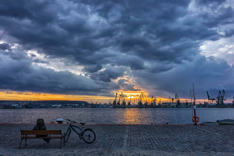 男人。自行车坐着板凳上港欣赏日落日出