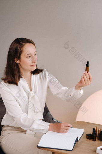 芳香疗法师女孩坐着办公室持有瓶芳香石油手写作至关重要的油表格