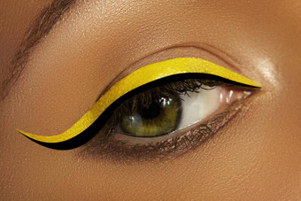 特写镜头女眼睛明亮的黄色的眼线笔化妆霓虹灯迪斯科化妆黑色的衬管夏天美风格