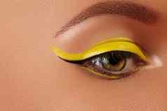 特写镜头女眼睛明亮的黄色的眼线笔化妆霓虹灯迪斯科化妆时尚修指甲夏天美风格