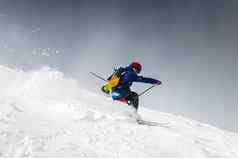 滑雪滑雪活泼的自由滑雪男人。时髦滑雪雪坡雪灰尘羽
