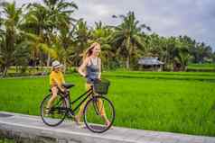 妈妈。儿子骑自行车大米场乌布巴厘岛旅行巴厘岛孩子们概念