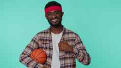 有胡子的快乐非洲美国年轻的男人。篮球体育运动风扇持有球相机