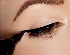 时尚女人应用眼线笔眼睑睫毛化妆刷形状黑色的行专业化妆艺术家