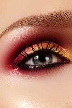 特写镜头女眼睛时尚明亮的化妆美丽的黄金红色的眼影闪闪发光的黑色的眼线笔形状眉毛