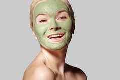 美丽的女人应用绿色面部面具美治疗特写镜头肖像水疗中心女孩应用粘土面部面具