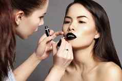 化妆艺术家准备美丽的女人时尚拍摄女孩应用嘴唇化妆萤光笔亚洲模型