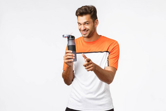 快乐的英俊的微笑运动员运动服指出相机咧着嘴笑持有瓶鼓励健身房成员喝水锻炼培训会话站白色背景
