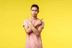 肖像优柔寡断困惑亚洲男人。显示指出横盘整理左变体选择穿粉红色的t恤皱着眉头困惑使选择黄色的背景