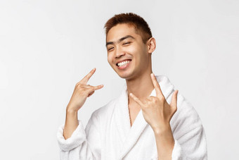 美水疗中心休闲概念肖像很酷的好看的亚洲男人。浴袍显示摇滚标志重metall微笑很高兴享受支出时间热弹簧假期时间