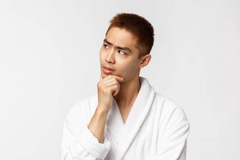 美水疗中心休闲概念肖像深思熟虑的亚洲男人。穿浴袍处理信息思考思考选择使重要的决定白色背景