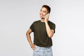 技术在线生活方式沟通概念英俊的快乐的中国人的家伙绿色t恤会说话的电话笑微笑乐观的站灰色背景