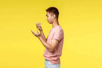 技术沟通生活方式概念配置文件肖像亚洲赶时髦的人的家伙粉红色的t恤移动电话离开的声音消息说话演讲者智能手机黄色的背景
