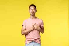 人情绪生活方式概念微笑感动了亚洲男人。时尚的发型粉红色的t恤持有手心相机很高兴假期黄色的背景