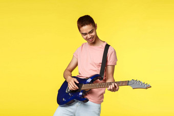 生活方式休闲青年概念肖像快乐很酷的时尚的亚洲的家伙玩乐队享受香水电吉他微笑热情的站黄色的背景