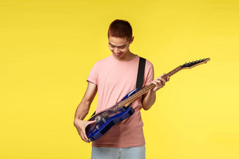 生活方式休闲青年概念肖像热情的亚洲的家伙收到电吉他礼物微笑快乐内衬满意很高兴黄色的背景