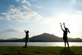 孩子们飞行风筝运行草地湖日落妈妈。健康的夏天活动孩子们有趣的时间家庭