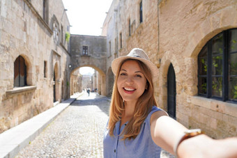 快乐微笑旅行者女孩采取自拍街骑士罗兹城市希腊年轻的女旅行者参观南部欧洲