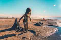 可爱的女孩针织泳衣玩沙子海滨