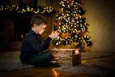 男孩打开神奇的一年的礼物圣诞节室内圣诞节树